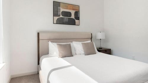 un letto bianco con cuscini bianchi in una camera da letto di Landing Apartments - Cedar Lakes a Duncanville