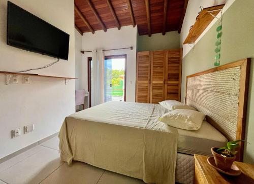 a bedroom with a bed and a flat screen tv at Casa Vila São Miguel in Itacaré