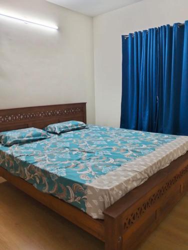 a bed in a room with a blue curtain at Elegant Stay at Bangalore International Airport in Bangalore