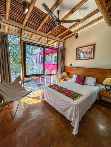 a bedroom with a bed and a chair and a window at Los Suspiros Hotel Boutique & Spa in Comala