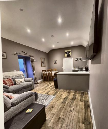 a living room with a couch and a kitchen at Y Beudy Bach in Kidwelly
