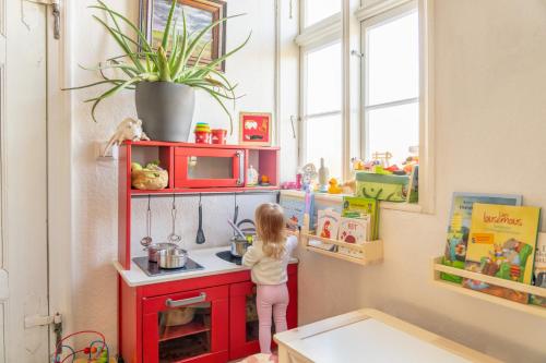 Een klein meisje staat in een speelgoedkeuken. bij Alandblick Gasthaus in Wanzer