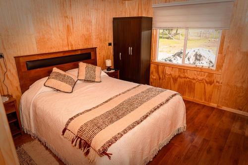 une chambre avec un grand lit avec une fenêtre dans l'établissement Cabañas Altos de Ñida, à Aytuy