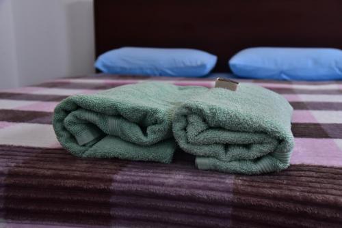 een groene handdoek bovenop een bed bij Misty Clouds Homestay in Kandy