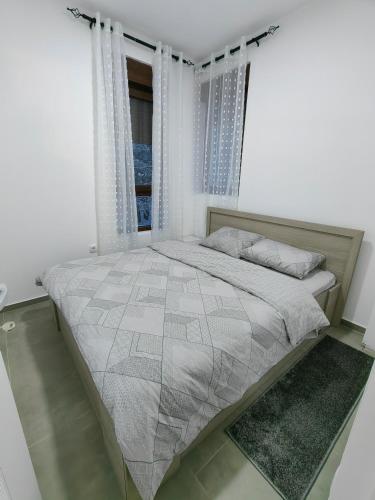 a bed in a white room with a window at Vidak apartman in Divčibare