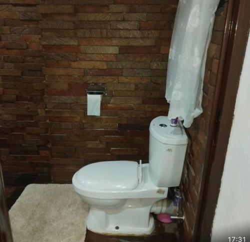 een badkamer met een toilet en een bakstenen muur bij The Retreat in Lusaka