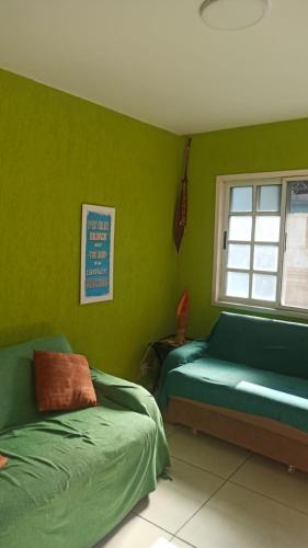 a green bedroom with two beds and a window at Jardim Caribenho in Arraial do Cabo