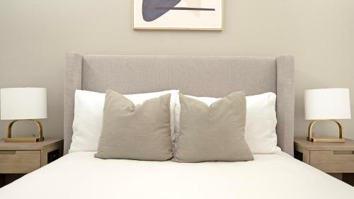 una camera da letto con un letto bianco con due lampade di Landing Chic 1BD Pool Gym a Black Horse Run