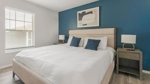 a bedroom with a large white bed with blue walls at Landing Apartments - The Carlisle at Dunedin in Dunedin