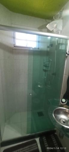 a bathroom with a glass shower and a sink at Jardim Caribenho in Arraial do Cabo