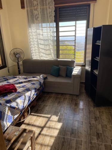 een woonkamer met een bank en een raam bij Lion's Den Chaletاستراحة وشاليه في جرش in Jerash