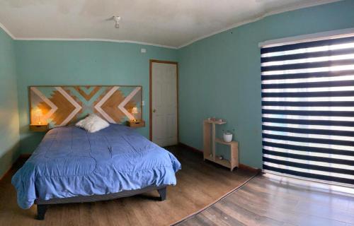 a bedroom with a bed and a blue wall at Casa Lepeley Colimilla in Frutillar
