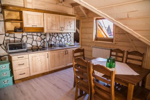 a kitchen and dining room with a table in a cabin at Apartamenty i pokoje Pod Limbami - sauna, tężnia in Bukowina Tatrzańska