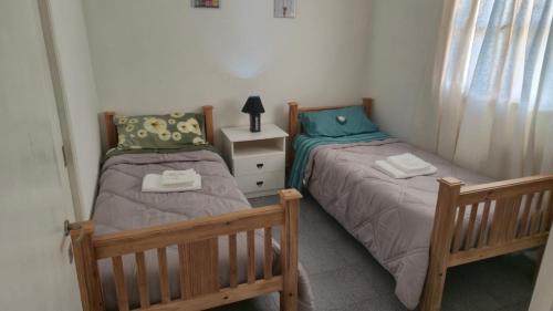 2 Einzelbetten in einem Schlafzimmer mit einem Nachttisch in der Unterkunft Valle del Río Chico in Gobernador Gregores