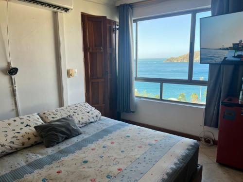 een slaapkamer met een bed met uitzicht op de oceaan bij Alojamiento Peñón del rodadero in Santa Marta