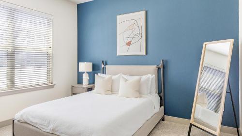 een slaapkamer met blauwe muren en een bed met een spiegel bij Landing Stunning 2BD Courtyard Gym in Denton