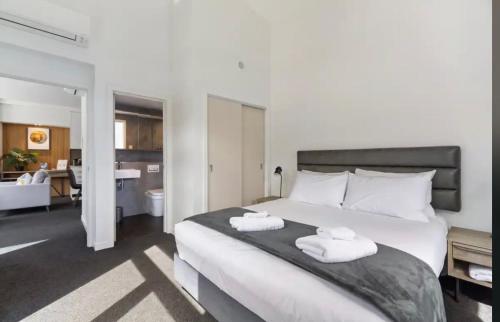 a bedroom with a large bed with towels on it at Modern Luxury Condo Shotover Views in Queenstown