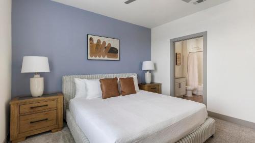 a bedroom with a white bed and a blue wall at Landing Apartments - Atlas Bluewood in Celina