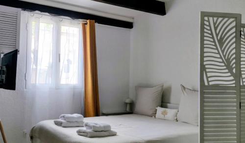 ein weißes Schlafzimmer mit einem Bett mit Handtüchern darauf in der Unterkunft La Nina A 5 min de Cassis in Roquefort-la-Bédoule