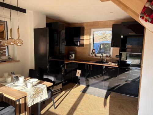 una cucina con armadi neri, tavolo e finestra di Apartamenty Słowianka-Chatka pod lasem a Wolibórz