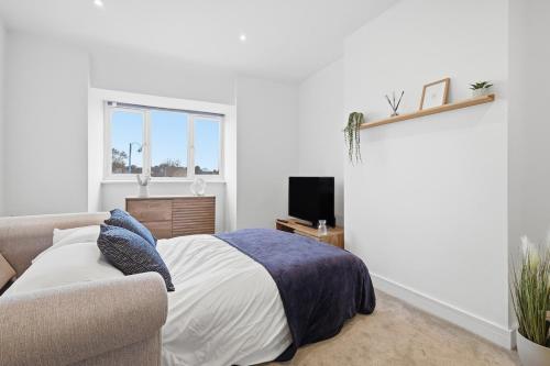 a bedroom with a bed and a couch and a television at Central Apartment - 16 Mins to London in Potters Bar