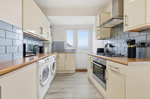 a kitchen with white cabinets and a washer and dryer at Central Apartment - 16 Mins to London in Potters Bar