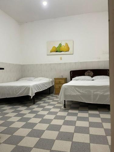 2 letti in una camera con pavimento a scacchi di Hotel Claveles Atlixco ad Atlixco