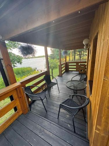 a porch with chairs and tables on a wooden building at Pasakų namelis in Svėdasai