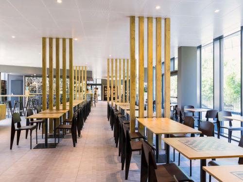una sala da pranzo con tavoli, sedie e finestre di ibis Baden Neuenhof a Baden