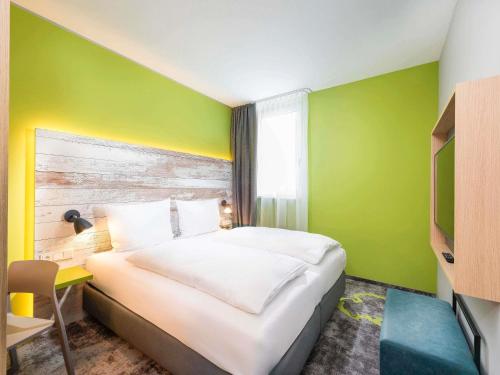 ein Schlafzimmer mit einem Bett und einer grünen Wand in der Unterkunft ibis Styles Stuttgart Vaihingen in Stuttgart