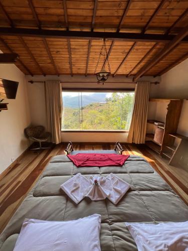 a large bed in a room with a large window at Chalés Vista das Montanhas in Lavras Novas
