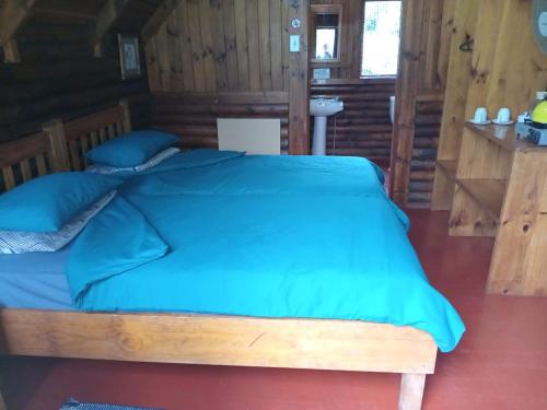 a bedroom with a large bed with blue sheets at Tannenhof Countryside Log Cabins in Sanddrif