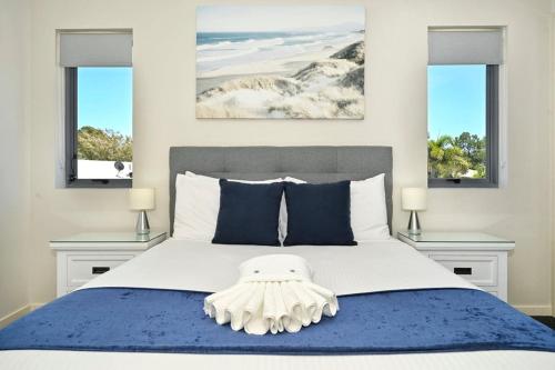 a bedroom with a large bed with two windows at Ocean Views Retreat, Caloundra in Caloundra