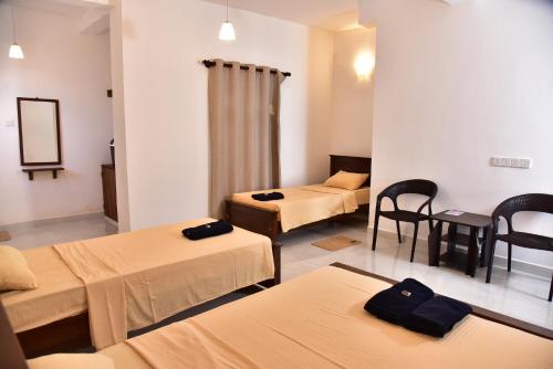een kamer met drie bedden en een tafel en stoelen bij Misty Clouds Homestay in Kandy