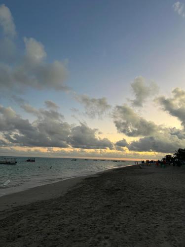 een strand met een bewolkte hemel en de oceaan bij Flats Brisa Antunes in Maragogi