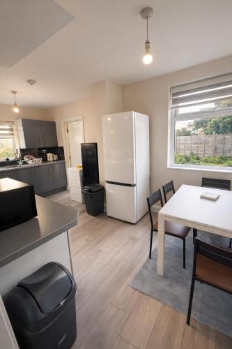 a kitchen with a white refrigerator and a table at Fina's House - Moments from Tottenham Hotspur Stadium in London