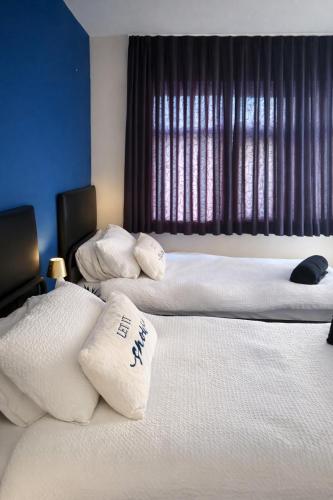 two beds in a hotel room with white pillows at Fina's House - Moments from Tottenham Hotspur Stadium in London