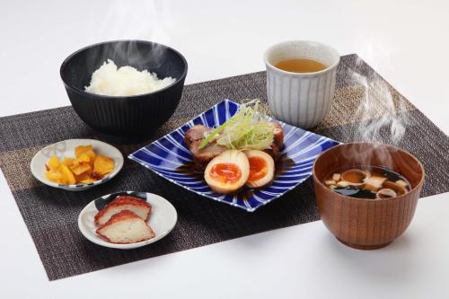 un piatto di cibo con sushi e una tazza di tè di Hotel Sunflex Kagoshima a Kagoshima