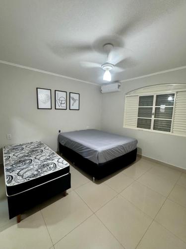 a bedroom with two beds and a ceiling fan at Casa Completa Para Dias Perfeitos in Olímpia