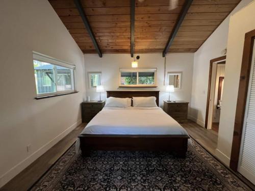 een grote slaapkamer met een groot bed en 2 ramen bij Secluded Lake Cottage with Hot Tub in Corralitos