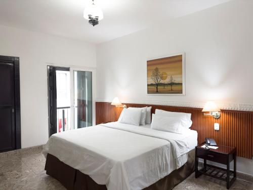 een slaapkamer met een groot bed met witte lakens bij Hotel Camino Real Popayán Colombia in Popayan