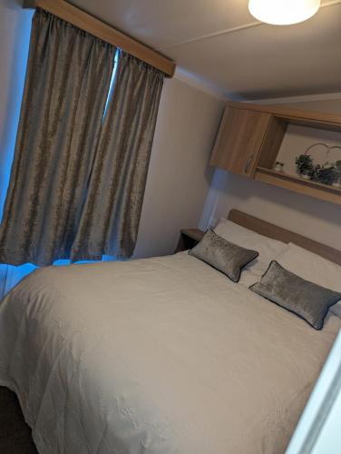 a bedroom with a bed with two pillows and a window at Denny's Holiday Homes in Blackpool