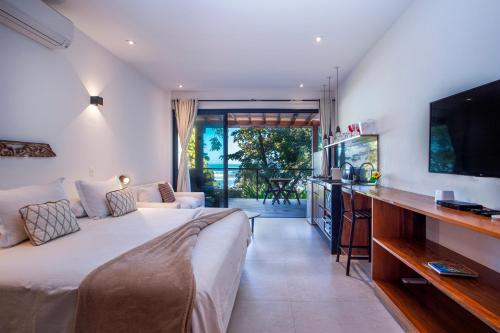 een slaapkamer met een bed en een keuken met een tv bij Flat Pitanga in Camburi