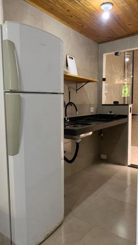 a white refrigerator in a kitchen with a counter at Embaúba Paraty - Hostel & Flats in Paraty