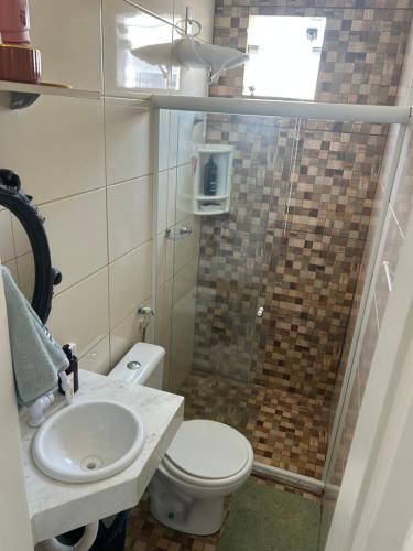 een badkamer met een douche, toilet en wastafel bij Arembepe Vilage Duplex in Camaçari