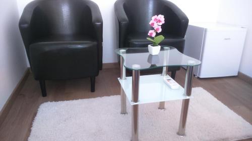two black chairs and a table with a vase of flowers on it at Vila Ema Apartments and Rooms in Ljubljana