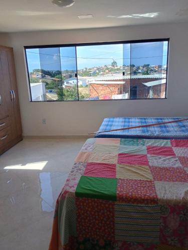 a bedroom with a bed and a large window at Regina in Cabo Frio