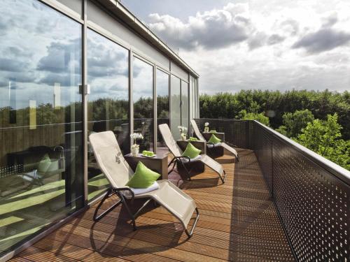 a balcony with chairs and tables on a building at Mövenpick Hotel Münster am Aasee in Münster