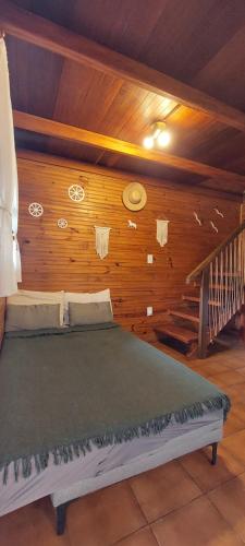 a bed in a room with a wooden wall at Chale Recanto do Lago in Itu