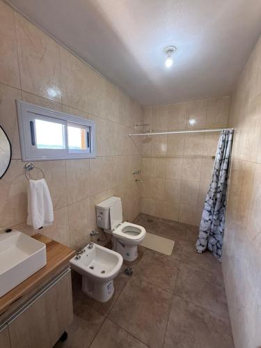 a bathroom with a white toilet and a sink at Cabañas La Caprichosa in Villa Santa Cruz del Lago